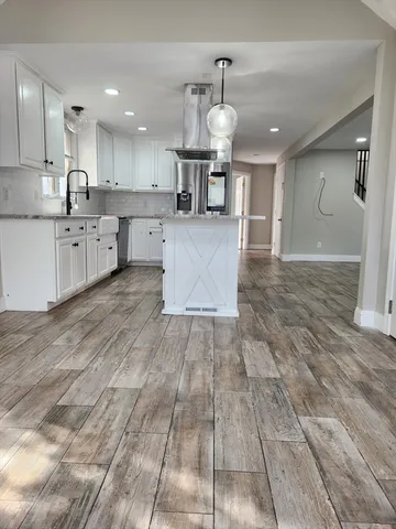 a large kitchen with stainless steel appliances kitchen island granite countertop a large counter top and wooden floors