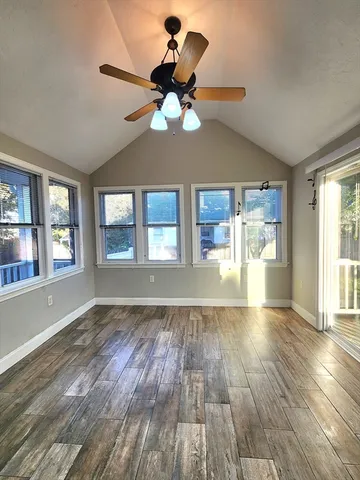 a view of an empty room with wooden floor and a window