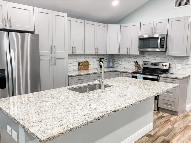 a kitchen with stainless steel appliances granite countertop a sink stove and refrigerator