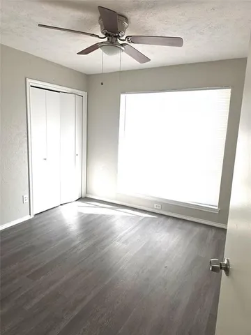 an empty room with wooden floor fan and windows