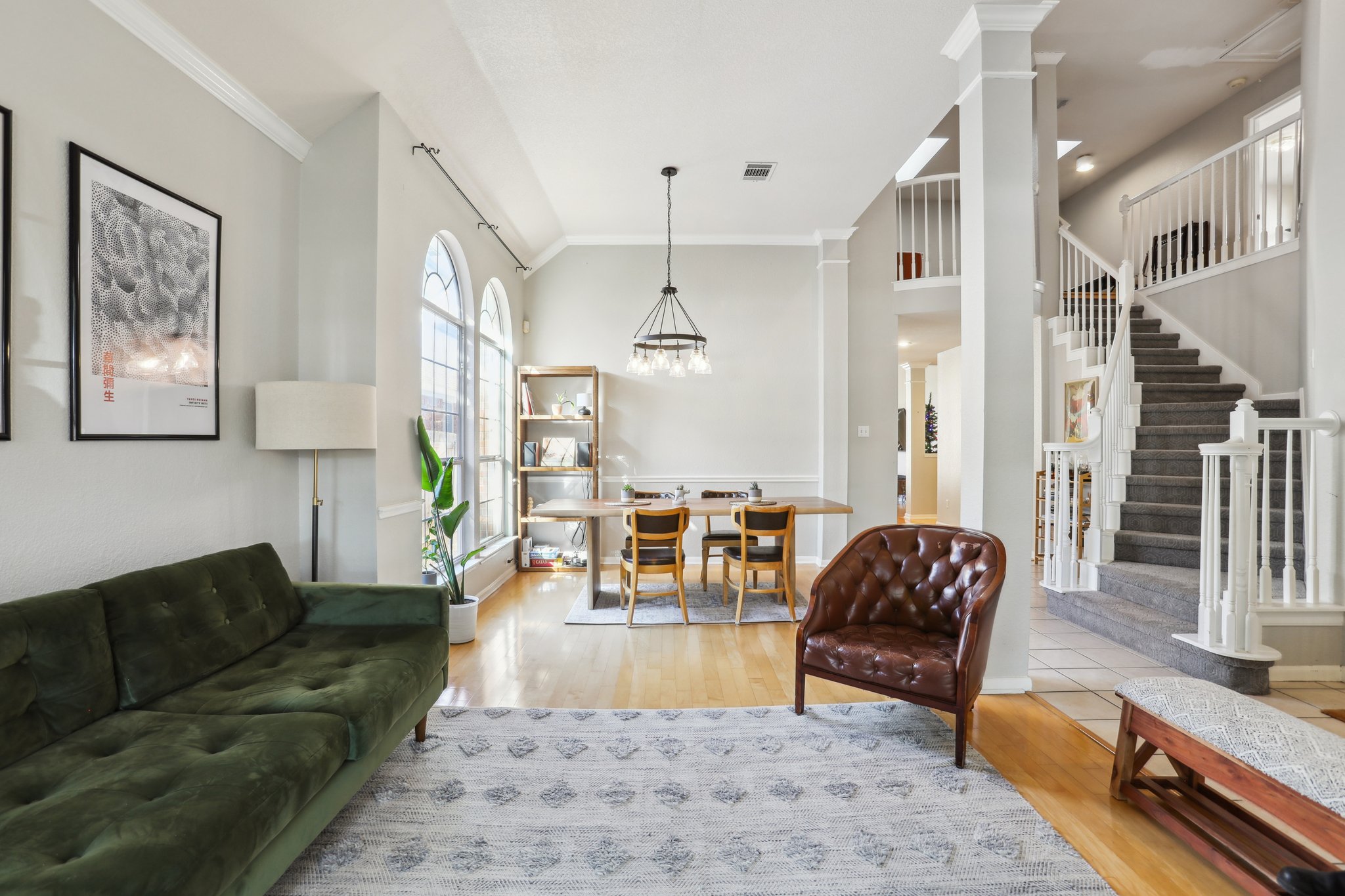 13541 Anarosa Loop Austin, TX 78727 - Photo 1 of 27 Open-concept living space with light wood-finish flooring, arched windows, and a staircase featuring white balusters and carpeted treads