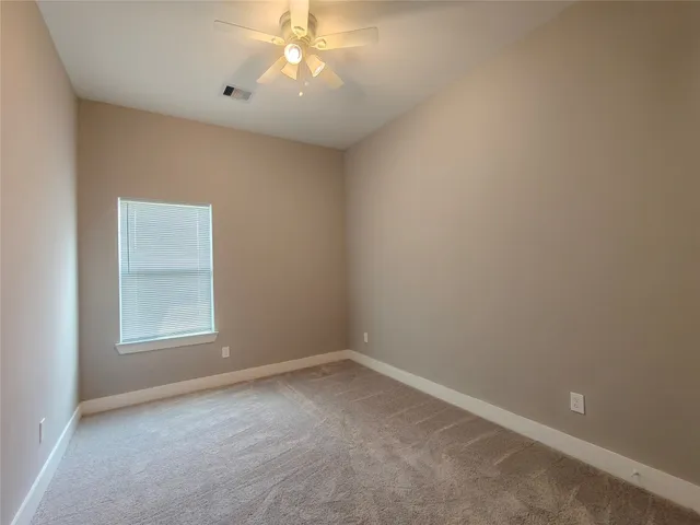 an empty room with a chandelier fan and a window