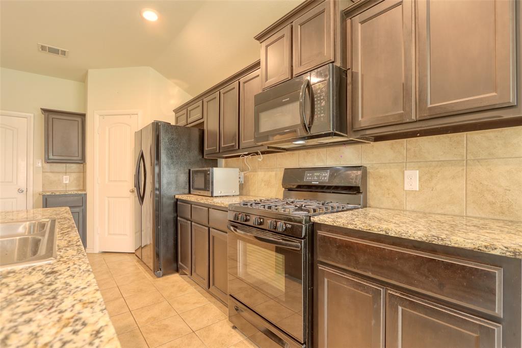 744 Walls Boulevard Crowley, TX 76036 - Photo 12 of 28 a kitchen with stainless steel appliances granite countertop a stove and a refrigerator