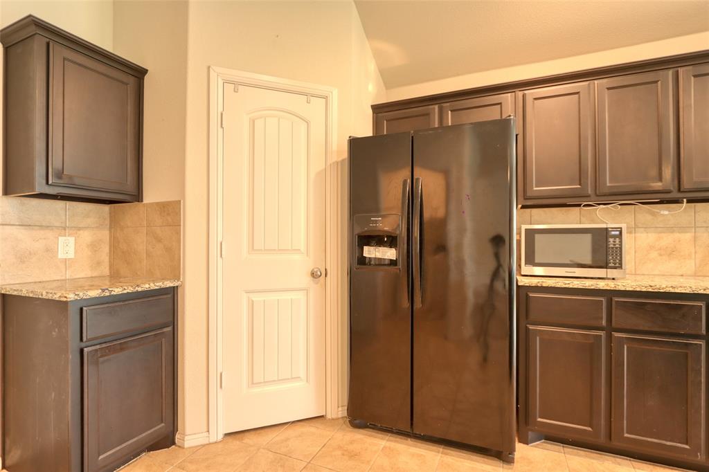 744 Walls Boulevard Crowley, TX 76036 - Photo 13 of 28 a kitchen with granite countertop a refrigerator and a sink