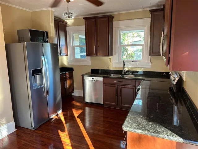 a kitchen with granite countertop stainless steel appliances a sink a counter space and a window