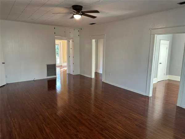 a view of an empty room with wooden floor and a window
