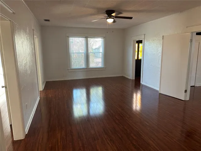 an empty room with wooden floor and windows