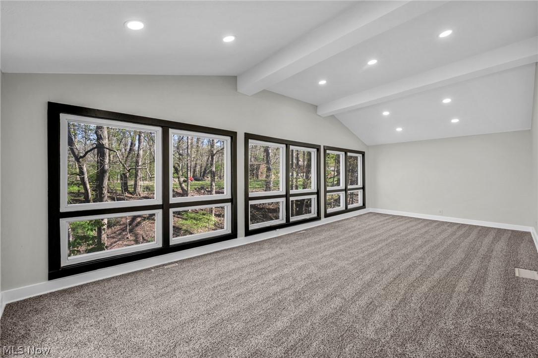7339 River Road Olmsted Falls, OH 44138 - Photo 16 of 45 Vaulted ceiling with exposed beams, recessed lighting, expansive picture windows with black trim, light gray wall color, and plush gray carpeting