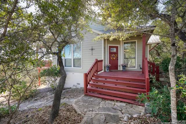 a view of a house with a small yard and large trees