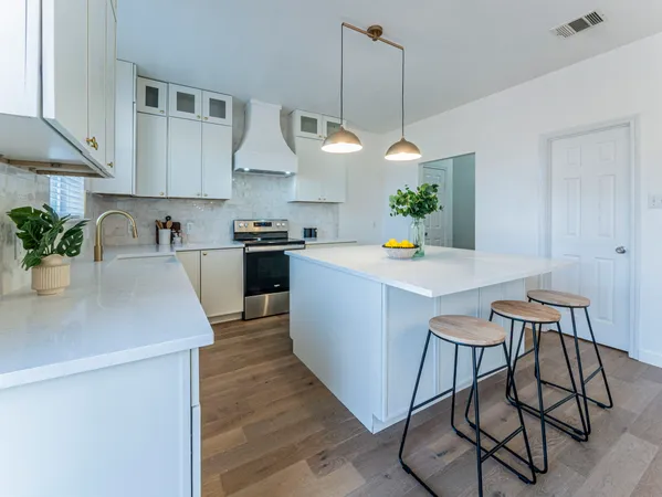 a kitchen with stainless steel appliances a table chairs refrigerator and cabinets