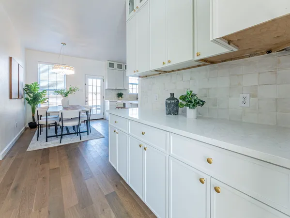 a kitchen with white cabinets and wooden floor