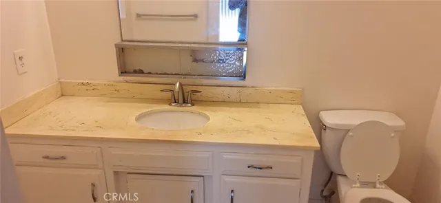 a bathroom with a granite countertop toilet sink and mirror