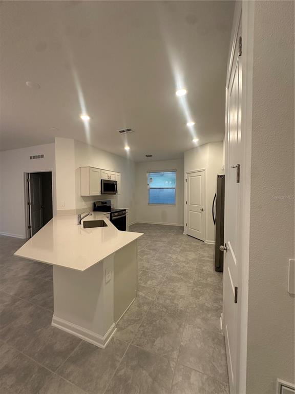 1623 Marksman Road Eagle Lake, FL 33839 - Photo 8 of 24 a large white kitchen with a refrigerator a stove a microwave and a sink