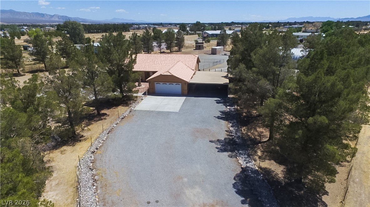 2381 Tough Boy Road Pahrump, NV 89060 - Photo 44 of 44 This elevated view captures a charming residence with a tiled roof, a large driveway, and surrounding greenery.