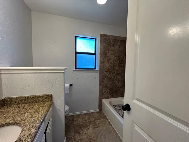 a bathroom with a granite countertop sink a toilet and shower