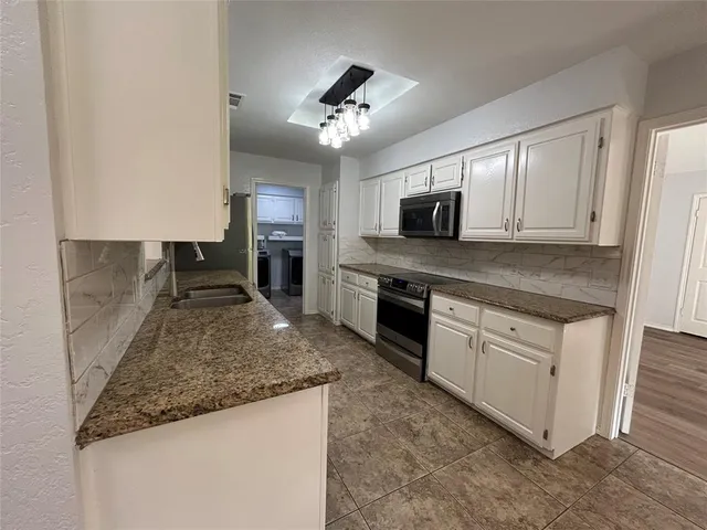 a kitchen with kitchen island granite countertop a stove sink and microwave