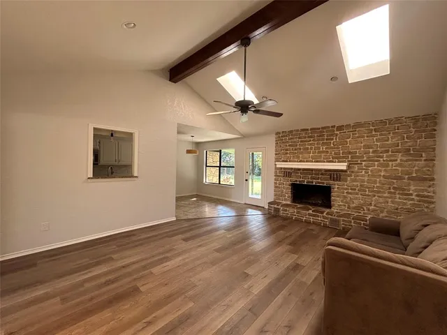 a view of empty room with fireplace and wooden floor
