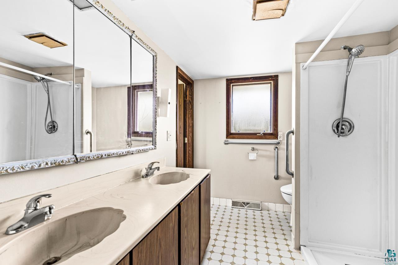 6606 Metso Road Kettle River, MN 55757 - Photo 15 of 84 Bathroom featuring a dual-sink vanity with an integrated countertop, wood-finish cabinetry, and chrome fixtures