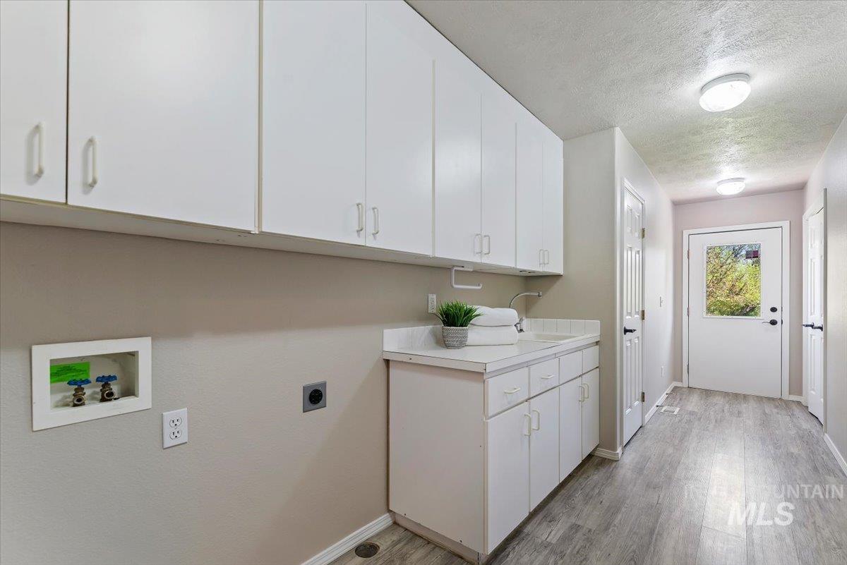 147 East Indian Crk Road Boise, ID 83716 - Photo 24 of 43 Laundry area featuring extensive white cabinetry, a built-in utility sink, a spacious countertop, wood-finish flooring, and direct outdoor access