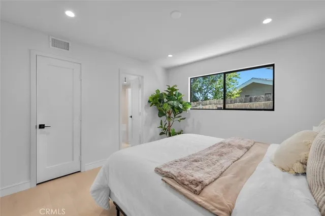 a bedroom with a large bed and a potted plant