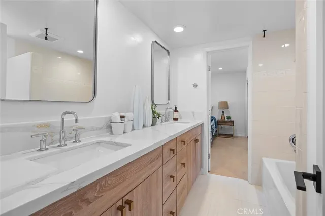 a spacious bathroom with a double vanity sink a mirror and a shower