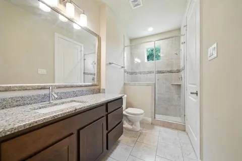 a bathroom with a granite countertop sink a toilet and a mirror