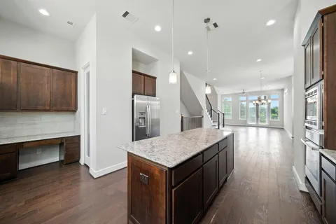 a kitchen with stainless steel appliances granite countertop a refrigerator a stove and a wooden floors