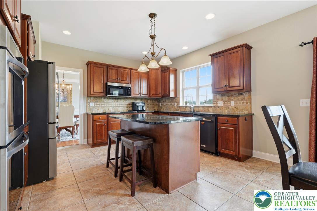245 East Dell Road Bath, PA 18014 - Photo 13 of 99 A well-lit kitchen boasts rich wood cabinetry, granite countertops, and a functional island, creating an inviting culinary space.