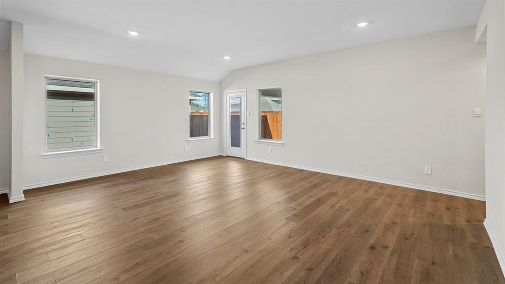 1953 Freeman Street Tyler, TX 75704 - Photo 12 of 32 Spacious room featuring wood-finish flooring, vaulted ceiling, recessed lighting, multiple windows, and a glass-paneled exterior door