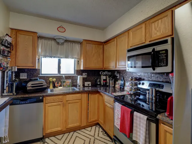 a kitchen with stainless steel appliances a sink a stove a refrigerator cabinets and a window