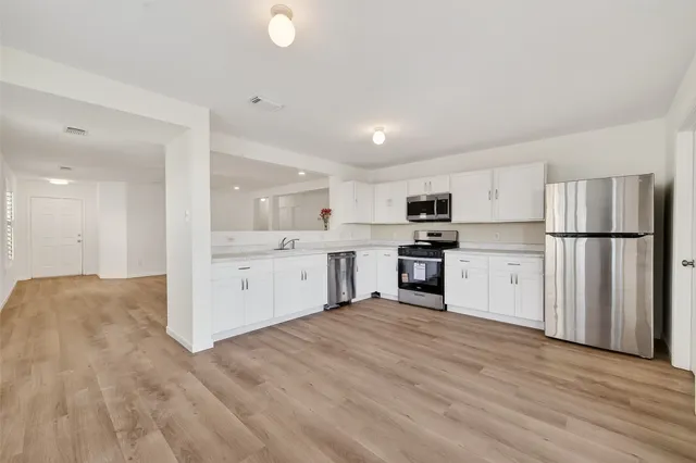 a kitchen with stainless steel appliances granite countertop a refrigerator sink and white cabinets