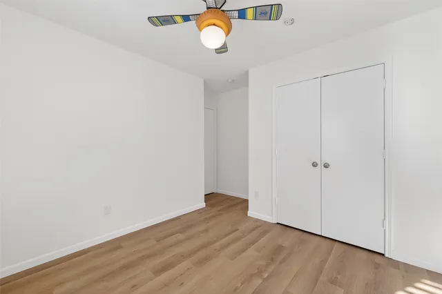a view of an empty room with wooden floor and window
