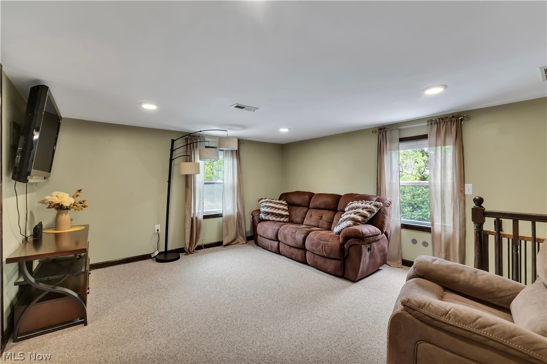 8704 Columbia Road Olmsted Falls, OH 44138 - Photo 12 of 34 Carpeted room featuring recessed lighting, a wooden stair railing, and two windows with natural light
