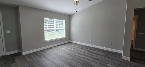 a view of an empty room with wooden floor and a window