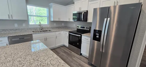 a kitchen with stainless steel appliances granite countertop a refrigerator a stove a sink and a window