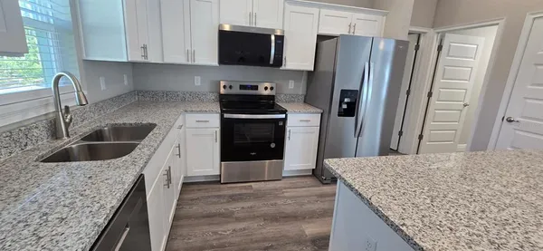 a kitchen with stainless steel appliances granite countertop a sink stove and refrigerator