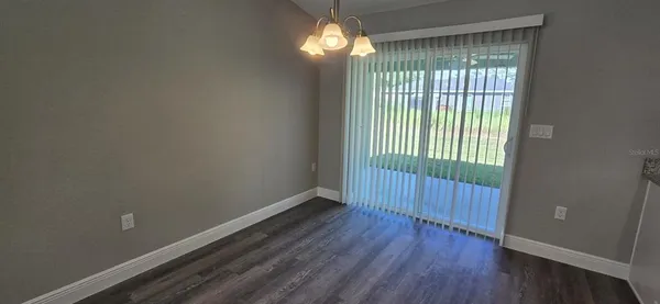a view of an empty room with wooden floor and fan