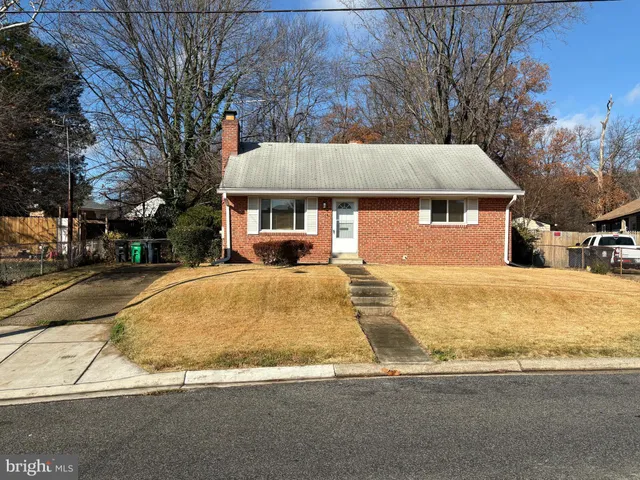 a view of a white house with a large tree next to a yard