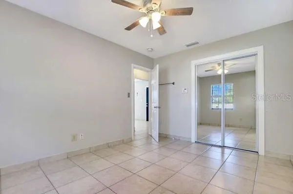 an empty room with closet and a chandelier fan