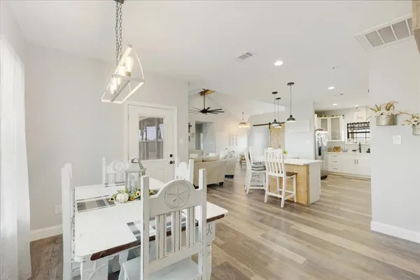 a view of a dining room and livingroom with furniture wooden floor a chandelier