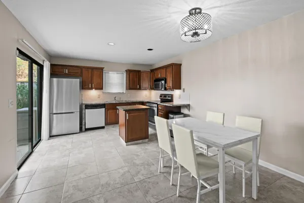 a kitchen with stainless steel appliances a table chairs and a refrigerator