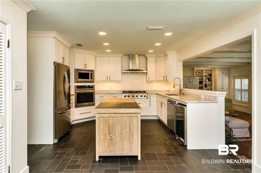 451 Ridgelawn Drive West Mobile, AL 36608 - Photo 39 of 41 Kitchen featuring appliances with stainless steel finishes, a sink, wall chimney range hood, butcher block countertops, and a kitchen island