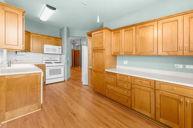 a kitchen with stainless steel appliances granite countertop a refrigerator a sink dishwasher and wooden cabinets with wooden floor