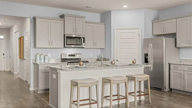 a kitchen with stainless steel appliances granite countertop a kitchen island a stove a cabinets and a refrigerator