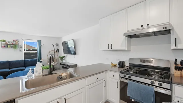a kitchen with stainless steel appliances a sink a stove and white cabinets