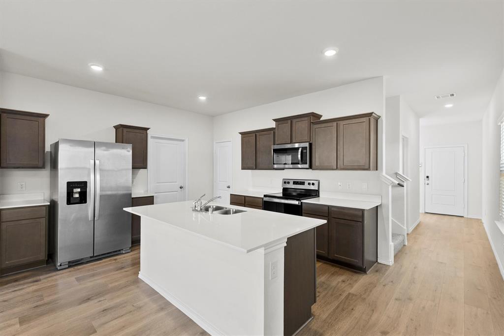 809 Trough Street Royse City, TX 75189 - Photo 8 of 38 a kitchen with stainless steel appliances a stove top oven a sink a refrigerator white cabinets and wooden floor