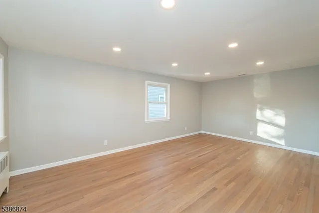 a view of an empty room with wooden floor and window