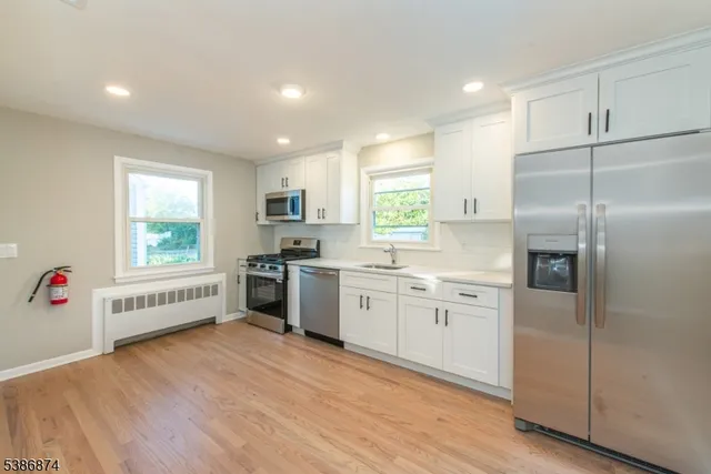 a kitchen with granite countertop white cabinets and stainless steel appliances