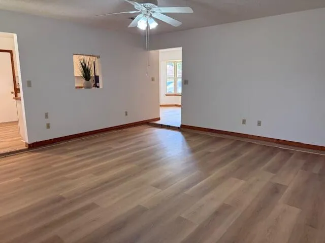 a view of an empty room with wooden floor and window