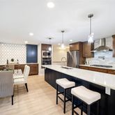 a kitchen with stainless steel appliances kitchen island granite countertop a table chairs sink and cabinets